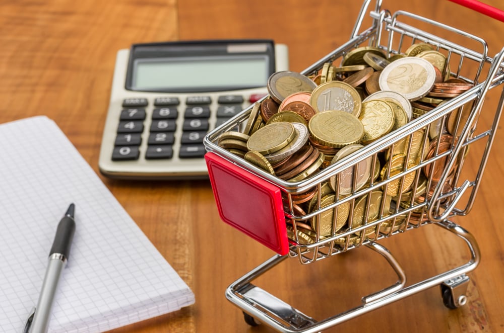 Shopping,Cart,Filled,With,Coins,On,A,Wooden,Desk